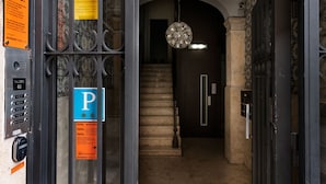 L’entrée d’un hôtel, dotée d’un clavier de sécurité, d’un panneau de signalisation bleu indiquant l’emplacement du parking et d’un escalier menant à un étage supérieur.