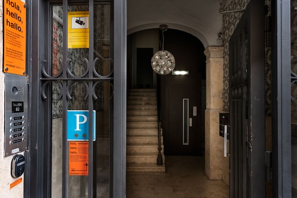 A hotel entrance with a security keypad, a blue parking sign, and a staircase leading to an upper floor. - Chic & Basic Tallers Hostal (Barcelona)