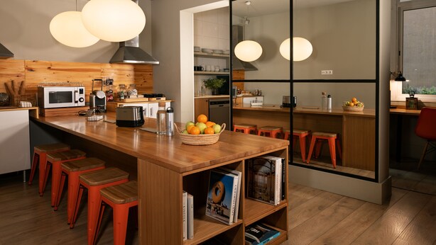 Une cuisine moderne avec des plans de travail en bois, un îlot central doté de tabourets, un four à micro-ondes et un grand miroir.