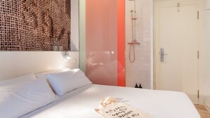 Une chambre d’hôtel avec un lit, une douche et un luminaire fixé au mur.