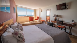 A hotel room with a large bed, a desk, a chair, and a TV.