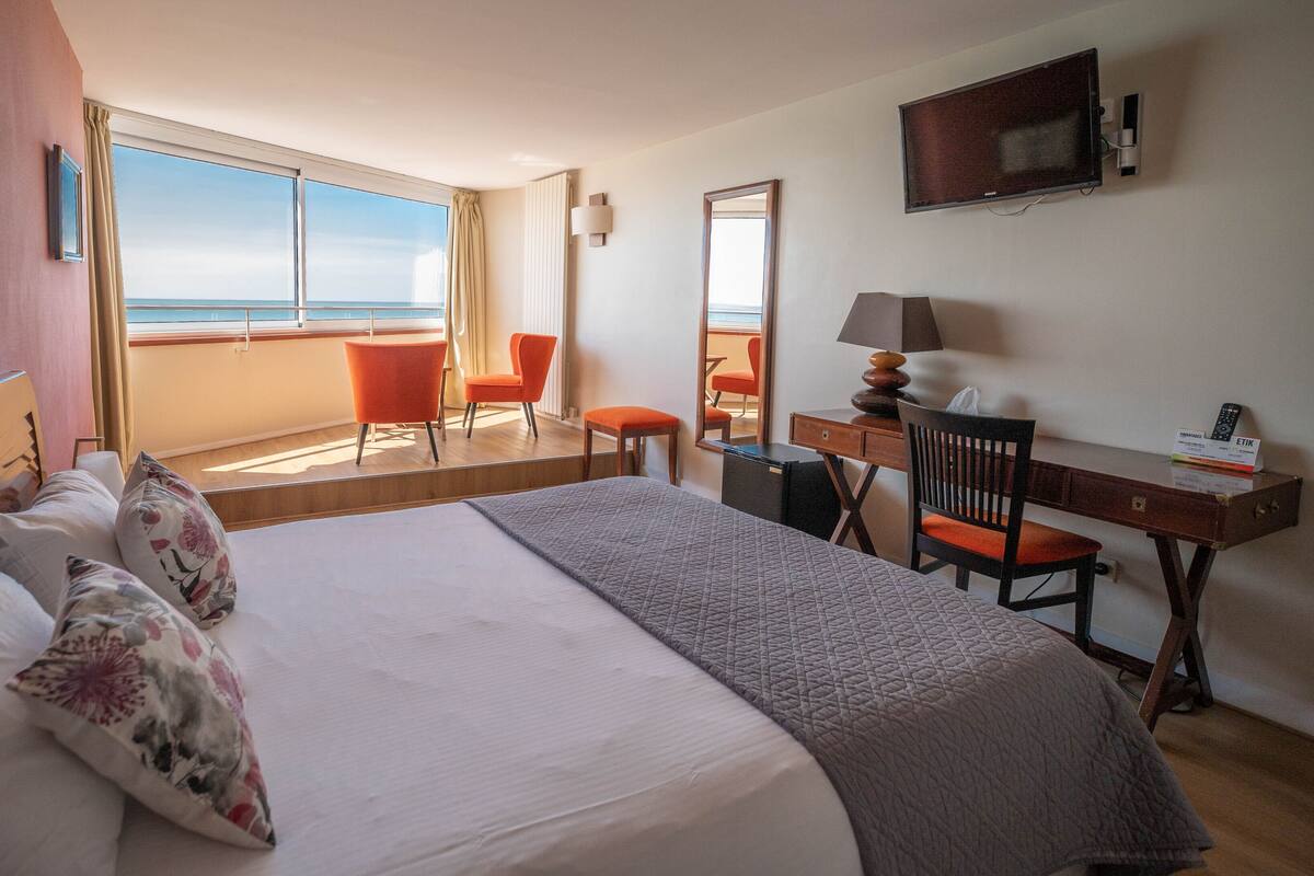 Una habitación de hotel con una cama grande, un escritorio, una silla y un televisor.
