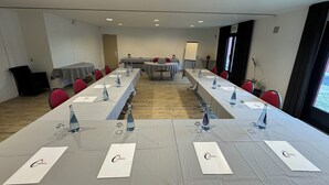 A conference room with long tables, chairs, and a whiteboard. - The Originals City, Hôtel Le Gayant (Douai)