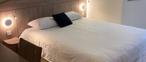 Una habitación de hotel con cama, mesita de noche y una silla.