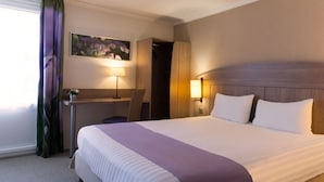 A hotel room with a large bed, a desk with a chair, a lamp, and a painting on the wall. - The Originals City, Hôtel Le Gayant (Douai)