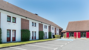 A row of two-story buildings with a parking lot in front. - The Originals City, Hôtel Le Gayant (Douai)