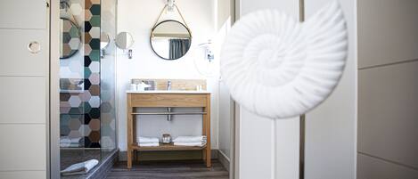 Un baño moderno con cabina de ducha de vidrio, tocador de madera y espejo redondo.