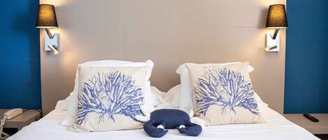 Ein Hotelzimmer mit einem Bett, zwei Wandlampen und zwei dekorativen Kissen mit Baum-Motiv.