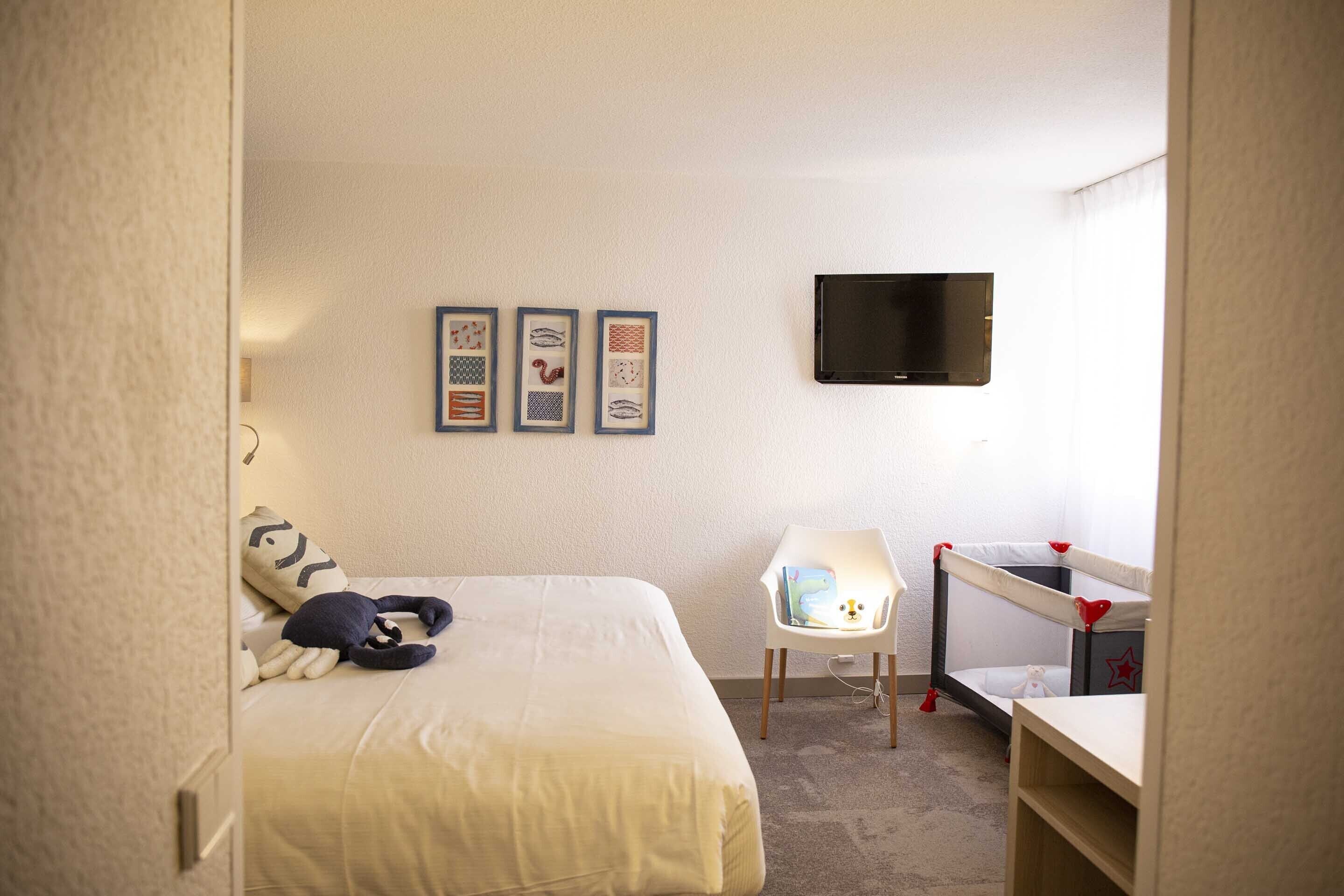 Une chambre à coucher avec un lit, un bureau, une chaise et un téléviseur fixé au mur.