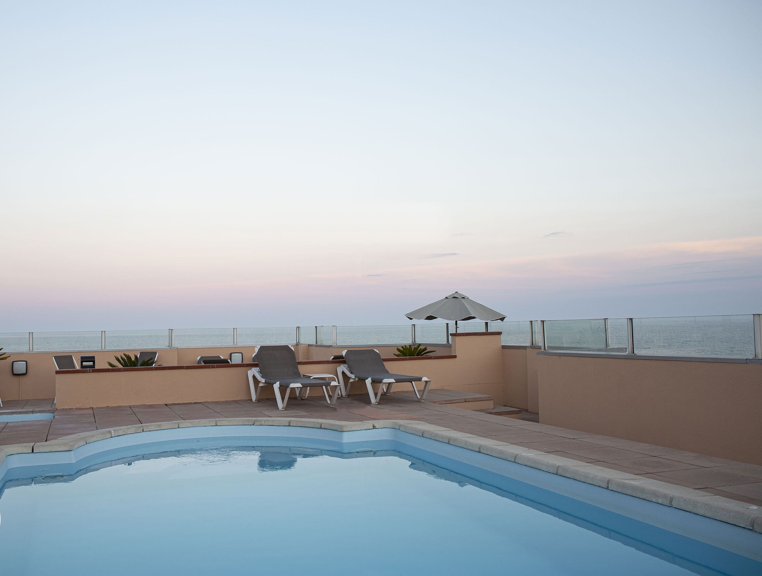 Una piscina con sillas de descanso y vista al océano.