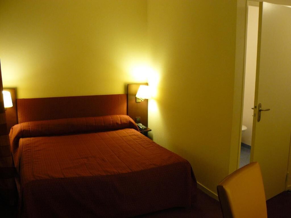 Et værelse med en stor seng, to sengeborde med lamper og en dør til et badeværelse.