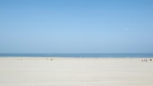 Een breed zandstrand met een heldere lucht.