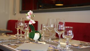 Een eettafel gedekt met verschillende wijnglazen, een vaas met witte bloemen en een menukaart.