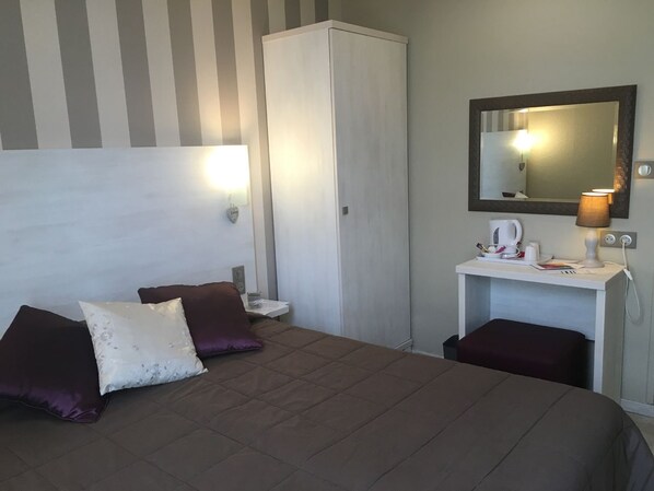 A hotel room with a bed, two pillows, a bedside table with a lamp, a wardrobe, and a mirror. - The Originals Boutique, Hôtel Neptune, Berck-sur-Mer (Berck-sur-Mer)
