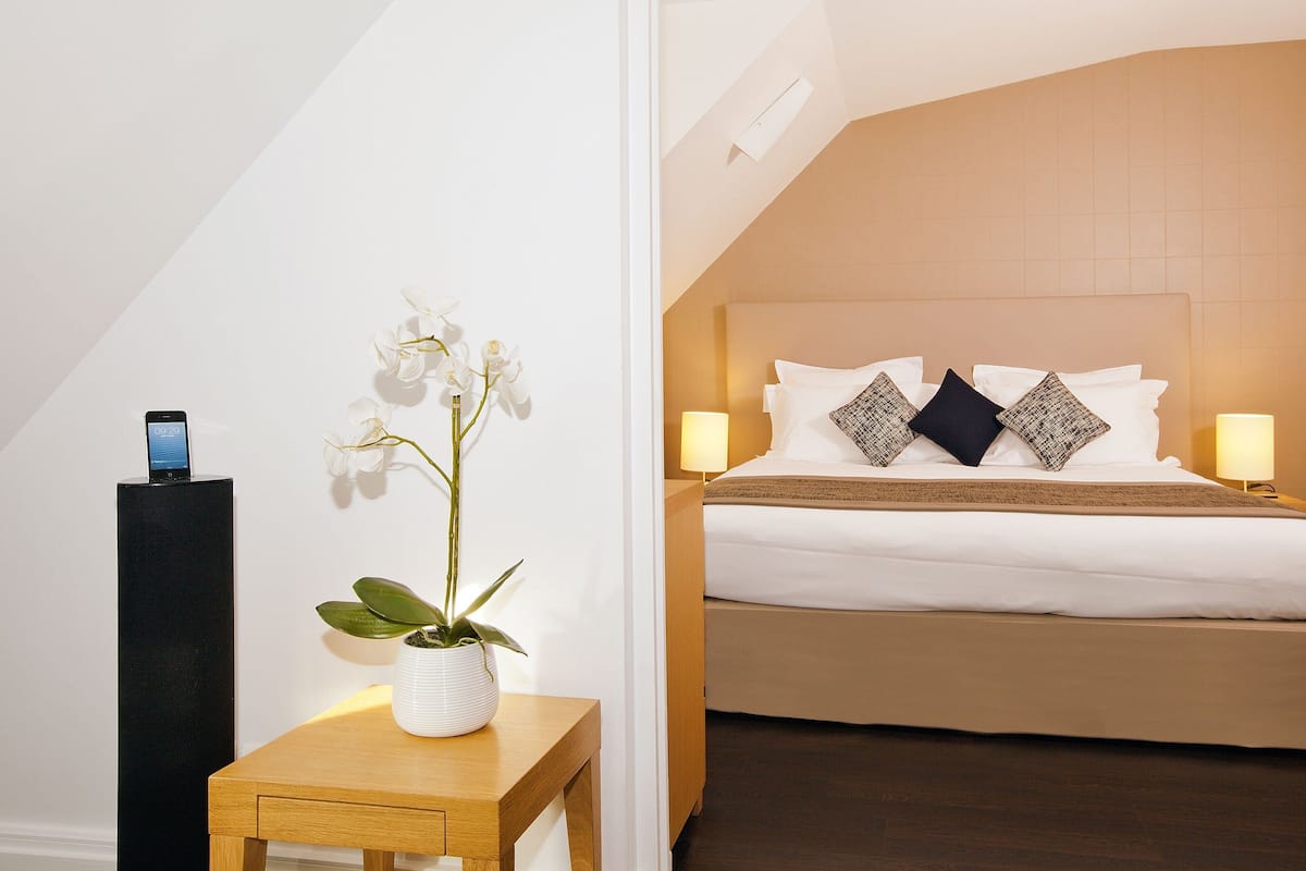 Une chambre d’hôtel avec un lit, des lampes de chevet, une table de chevet avec un téléphone et une orchidée en pot.