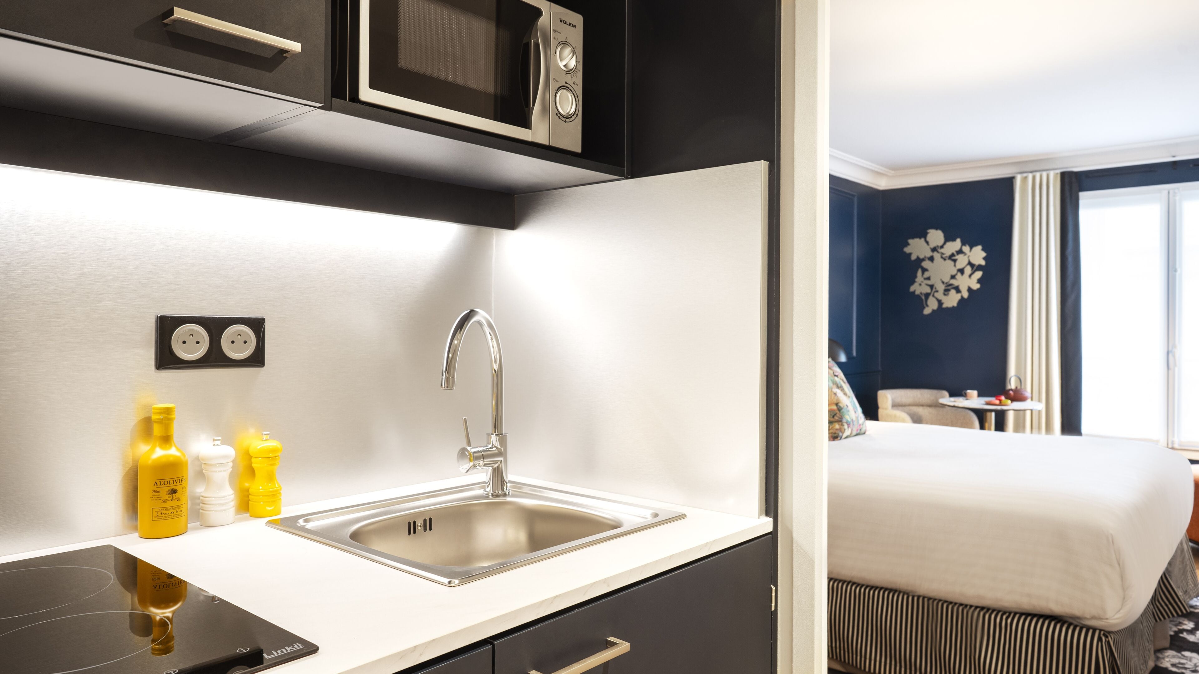 Una habitación de hotel moderna con kitchenette, una cama y vistas a la ciudad.