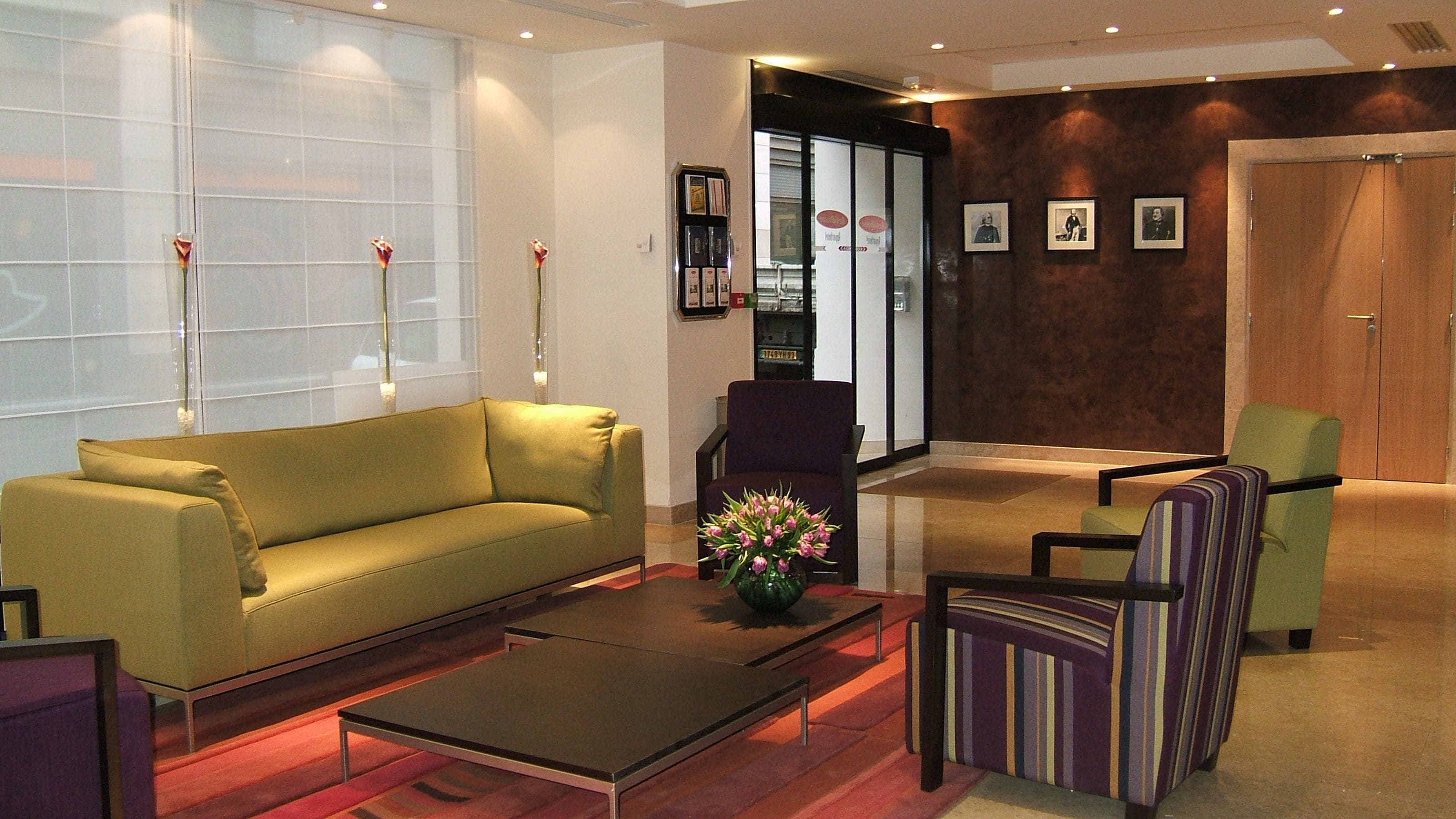 A modern lobby with a sofa, armchairs, a coffee table, and a vase of flowers.