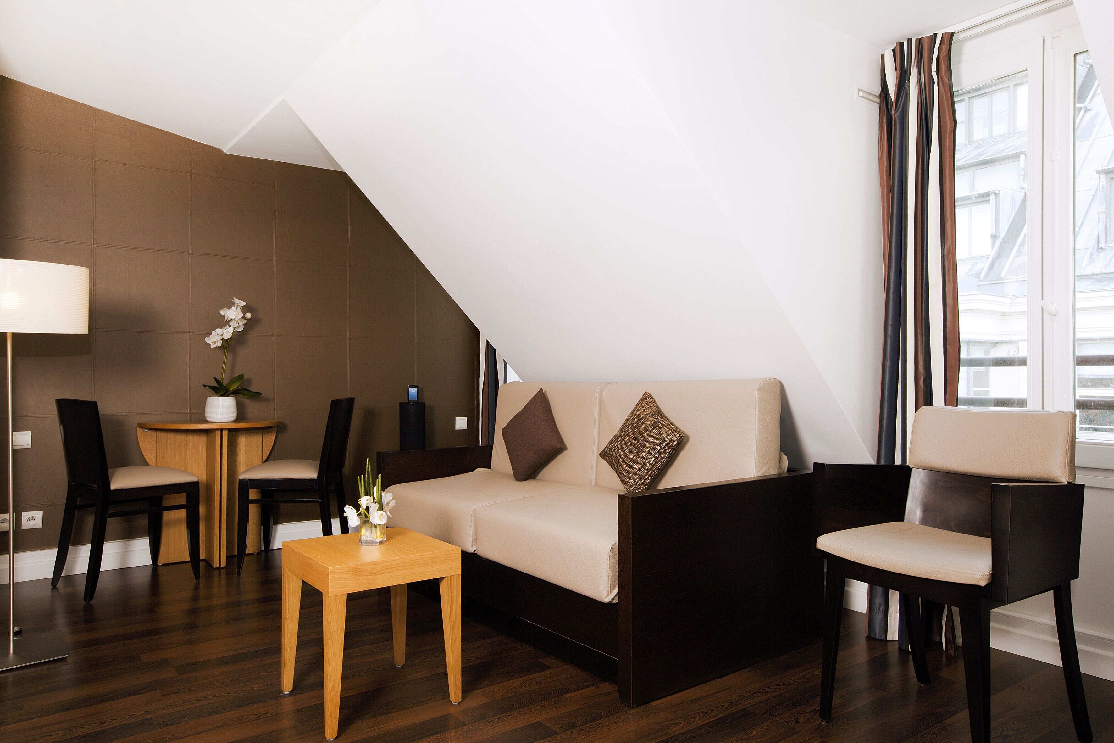 Un salon moderne comprenant un canapé, deux fauteuils, une petite table et une lampe.