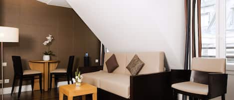 A modern living room with a sofa, two chairs, a small table, and a lamp.