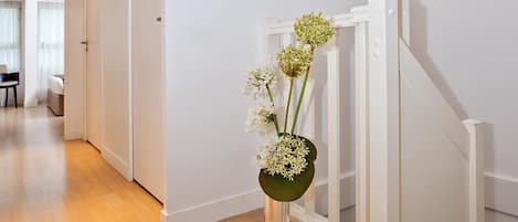 A hallway with wooden flooring, white walls, and a white staircase.