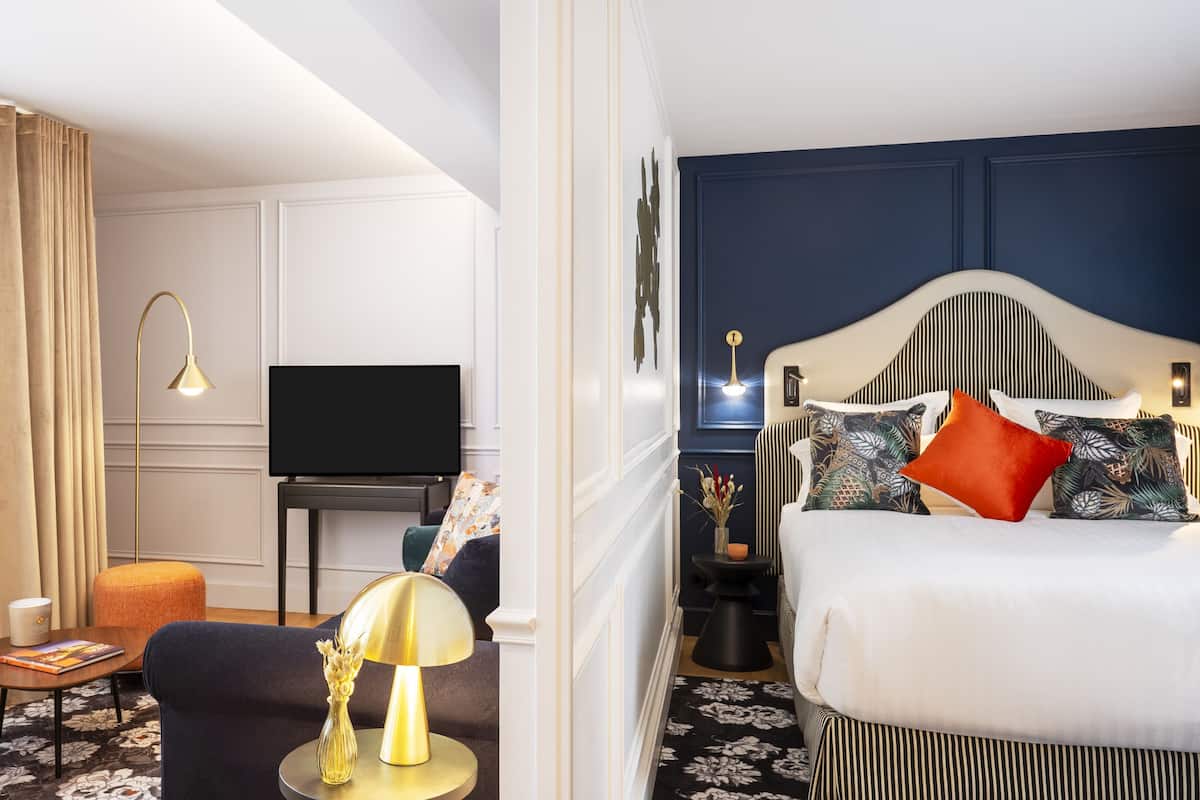 Une chambre d’hôtel avec un lit, une télévision, un bureau, une lampe et une chaise.