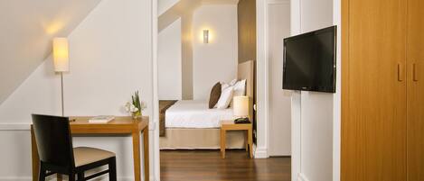Habitación de hotel con cama, escritorio con silla, televisor y armario de madera.