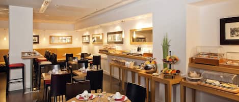 A hotel dining area with multiple tables, chairs, and a buffet setup.