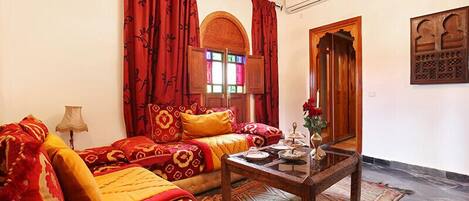 A traditional room with a sofa set, a wooden coffee table, and a window with stained glass.