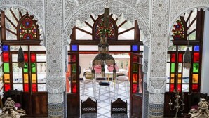 Une pièce aux murs ornés de motifs complexes en noir et blanc, avec une porte d’entrée centrale en arc de cercle et un lustre.