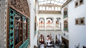 Une cour intérieure agrémentée d’arches décoratives, dotée d’un sol carrelé et d’un plafond haut avec une lucarne.
