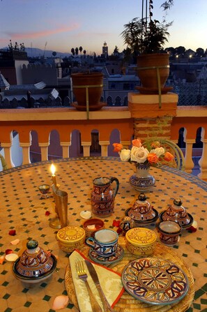 A table set for a meal with traditional Moroccan tableware, a potted plant, and a candle. - Riad Dalia (Marrakech)
