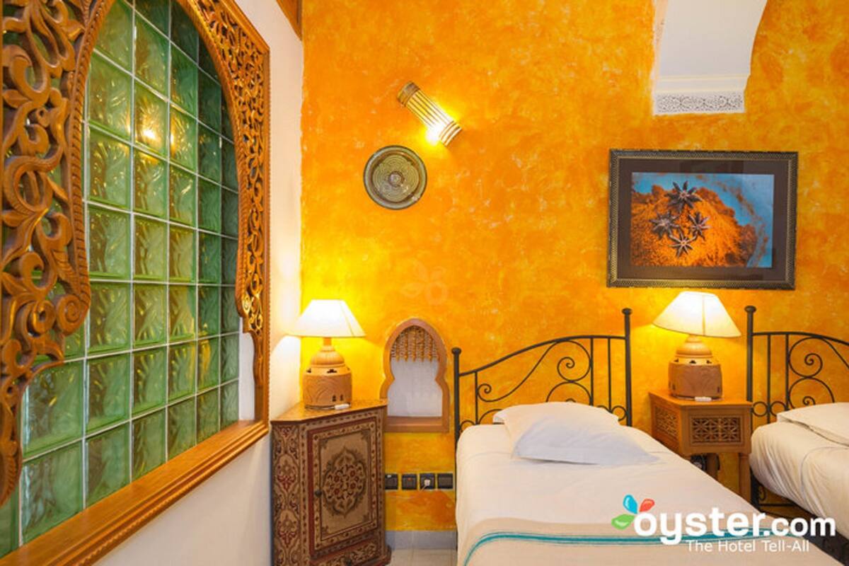 Habitación de hotel con cama, dos lámparas de noche, un diseño decorativo en la pared y un ventanal con vidrio esmerilado.