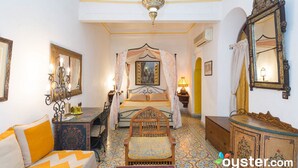 A traditional Moroccan room with a bed, a wooden chair, a nightstand, a mirror, and a chandelier. - Riad Maison Arabo-Andalouse (Marrakech)