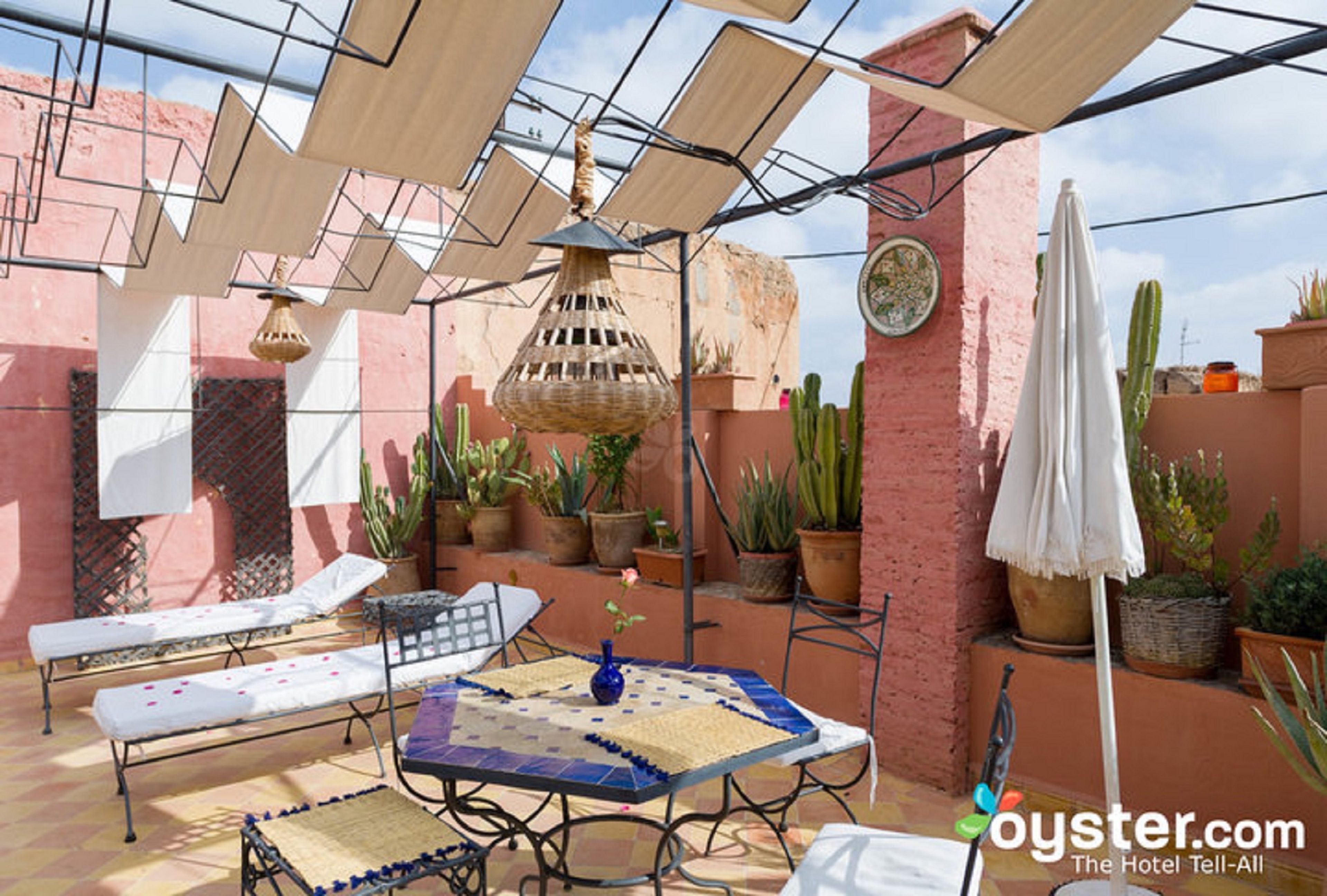 Un patio soleado con una mesa, sillones de descanso y plantas en macetas.