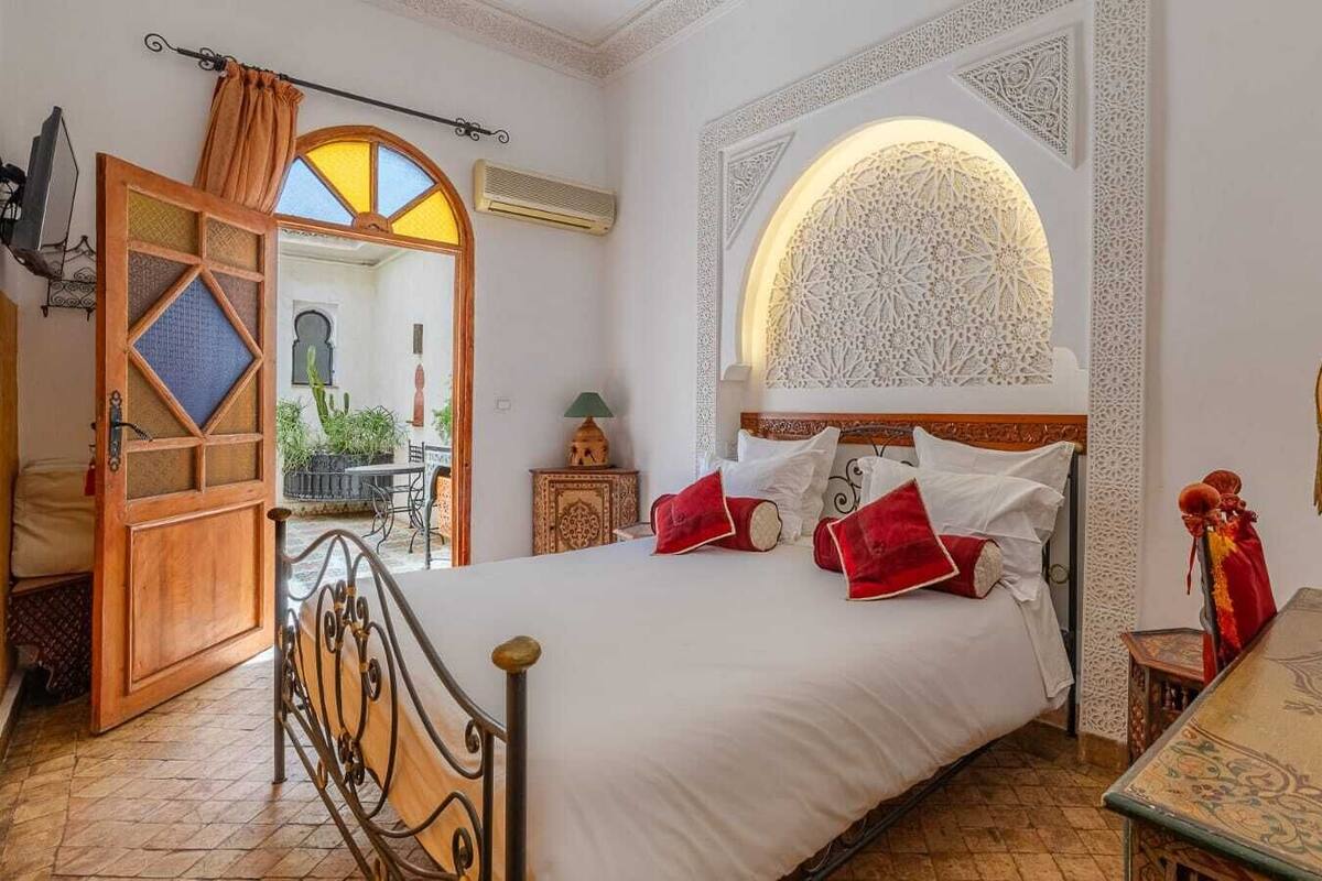 Un dormitorio con cama, mesita de noche, lámpara y decoración en la pared.