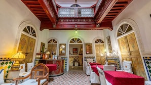 A traditional Moroccan interior with ornate doors, a central seating area with red and white textiles, and a patterned floor. - Riad Maison Arabo-Andalouse (Marrakech)
