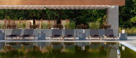 A pool area with lounge chairs and a pergola structure.