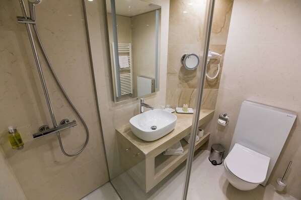 A modern bathroom with a glass-enclosed shower, a white sink, and a toilet.