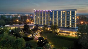 A modern hotel with a large glass facade, multiple floors, and a well-lit exterior.