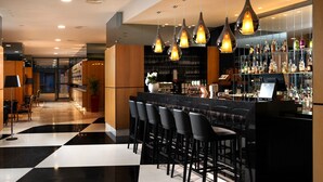 A bar area with black bar stools, a counter, and a glass display case of bottles.