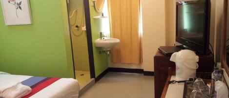A hotel room with a bed, a television, a sink, and a window with curtains.