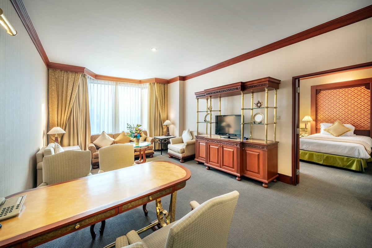 A hotel room with a dining area, a television, a bed, and a desk.