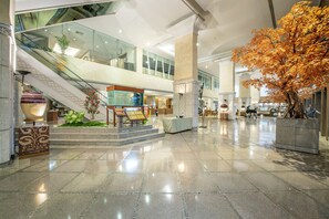 A spacious lobby with a polished floor, a staircase, and a large artificial tree. - Ramada by Wyndham Bangkok Chaophya Park (Bangkok)