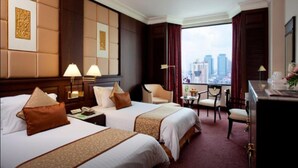 Habitación de hotel con dos camas, un escritorio, una silla y vistas a la ciudad.