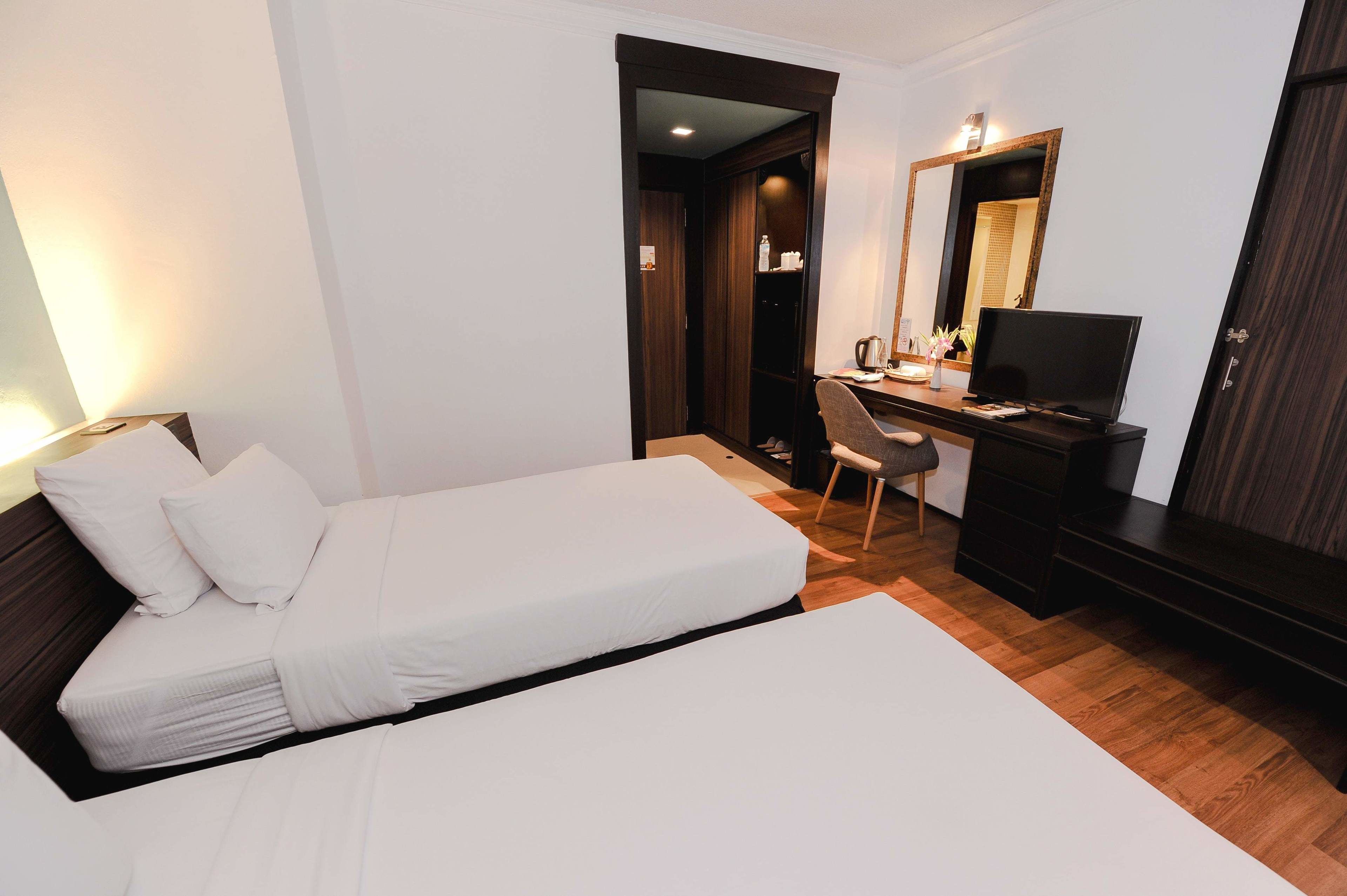 Een hotelkamer met een bed, een bureau, een stoel, een televisie en een kledingkast.