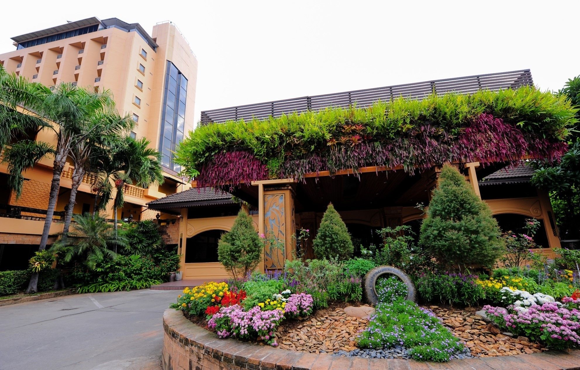 Un hotel con un diseño arquitectónico moderno, que cuenta con un jardín en la azotea con diversas plantas y flores.
