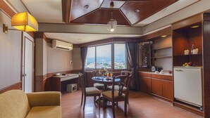 Une chambre d’hôtel comprenant un coin repas, un canapé, un lustre et une vue sur la ville.