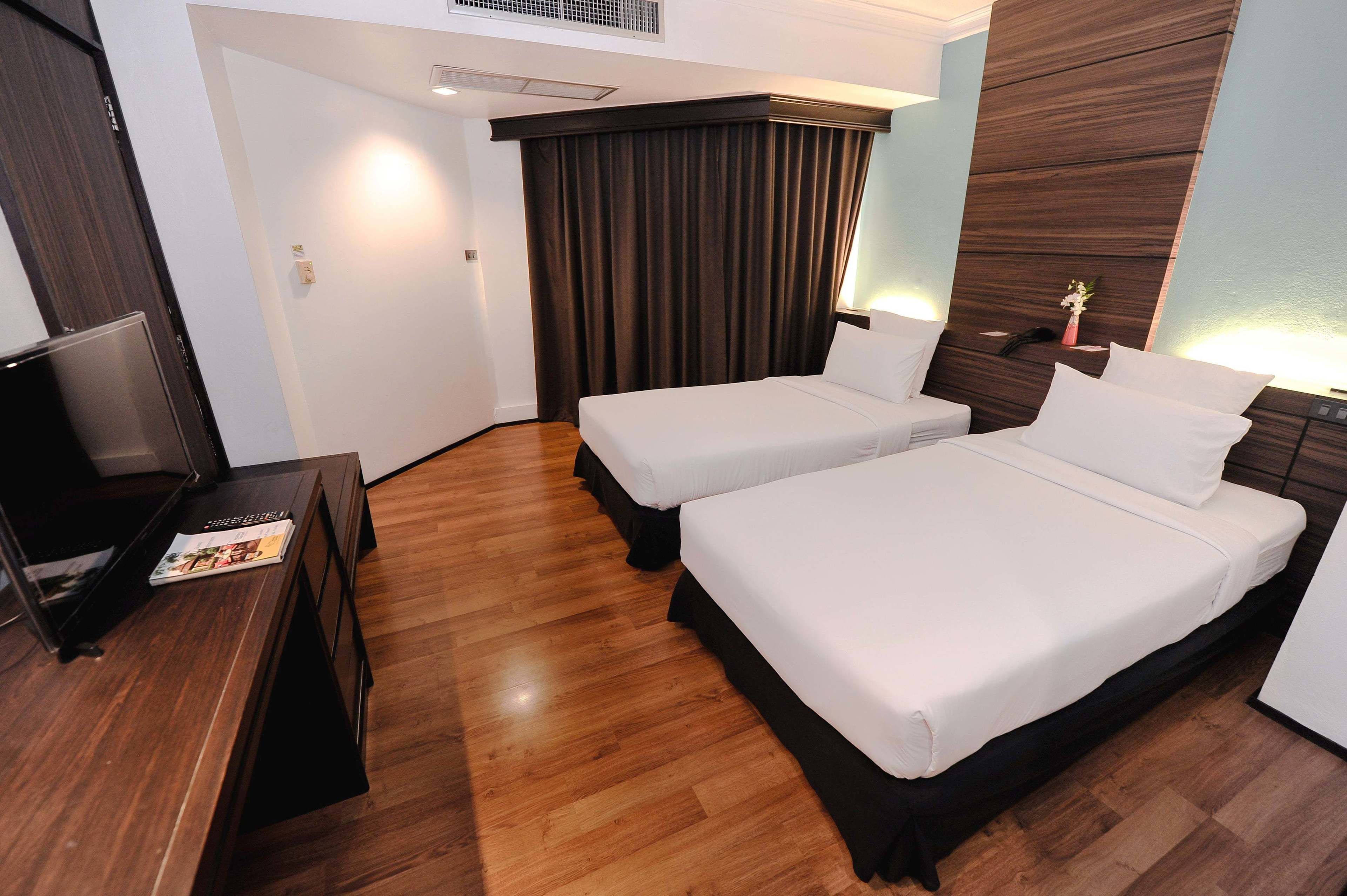 Une chambre d’hôtel avec deux lits, une télévision et un plancher en bois.