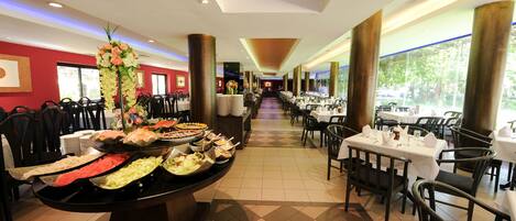 A buffet setup in a restaurant with multiple food stations, tables, and chairs arranged for dining.
