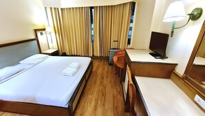 A hotel room with a bed, desk, chair, TV, curtains, and a lamp. - Bangkok City Inn (Bangkok)